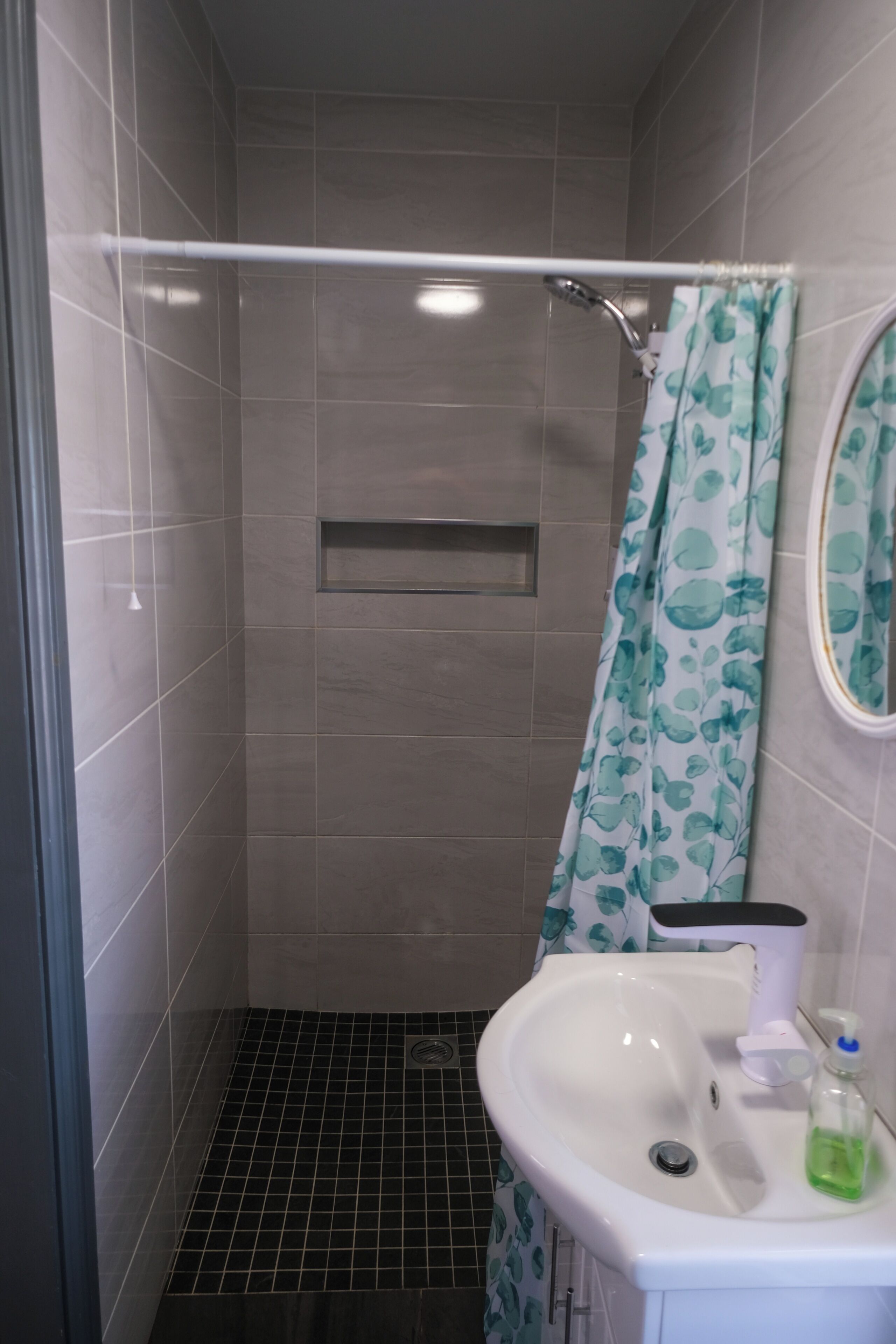 Un baño con ducha, lavabo y espejo.