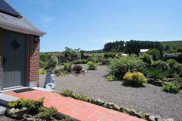 A building with a brick exterior, a gravel driveway, and a variety of landscaped garden beds.