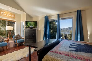 Ein Schlafzimmer mit einem Bett, einer Kommode, einem Fernseher und Blick ins Freie, sowie einem Schild mit der Aufschrift 'Relax'.