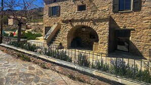 A stone building with a staircase, an arched entrance, and a small window. - Stone house with swimming pool in the heart of the Corsican mountains. Near Corte (Corscia)