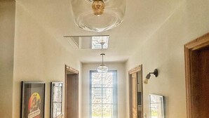 A hallway with a ceiling fan, framed pictures on the walls, and a door at the end. - Stone house with swimming pool in the heart of the Corsican mountains. Near Corte (Corscia)