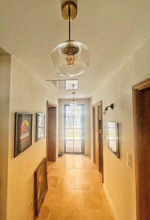A hallway with a ceiling fan, framed pictures on the walls, and a door at the end.