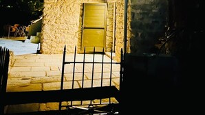 A stone building with a metal gate, a window, and a door. - Stone house with swimming pool in the heart of the Corsican mountains. Near Corte (Corscia)