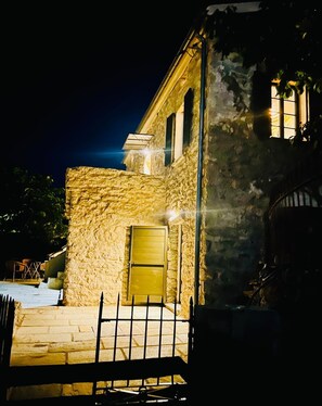 A stone building with a metal gate, a window, and a door.