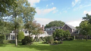 A large, multi-story building with a traditional architectural style, surrounded by well-maintained lawns and trees. - Charming Room Near Lochemse Berg, Ideal for Hiking, Forest walks, and Cycling (Lochem)