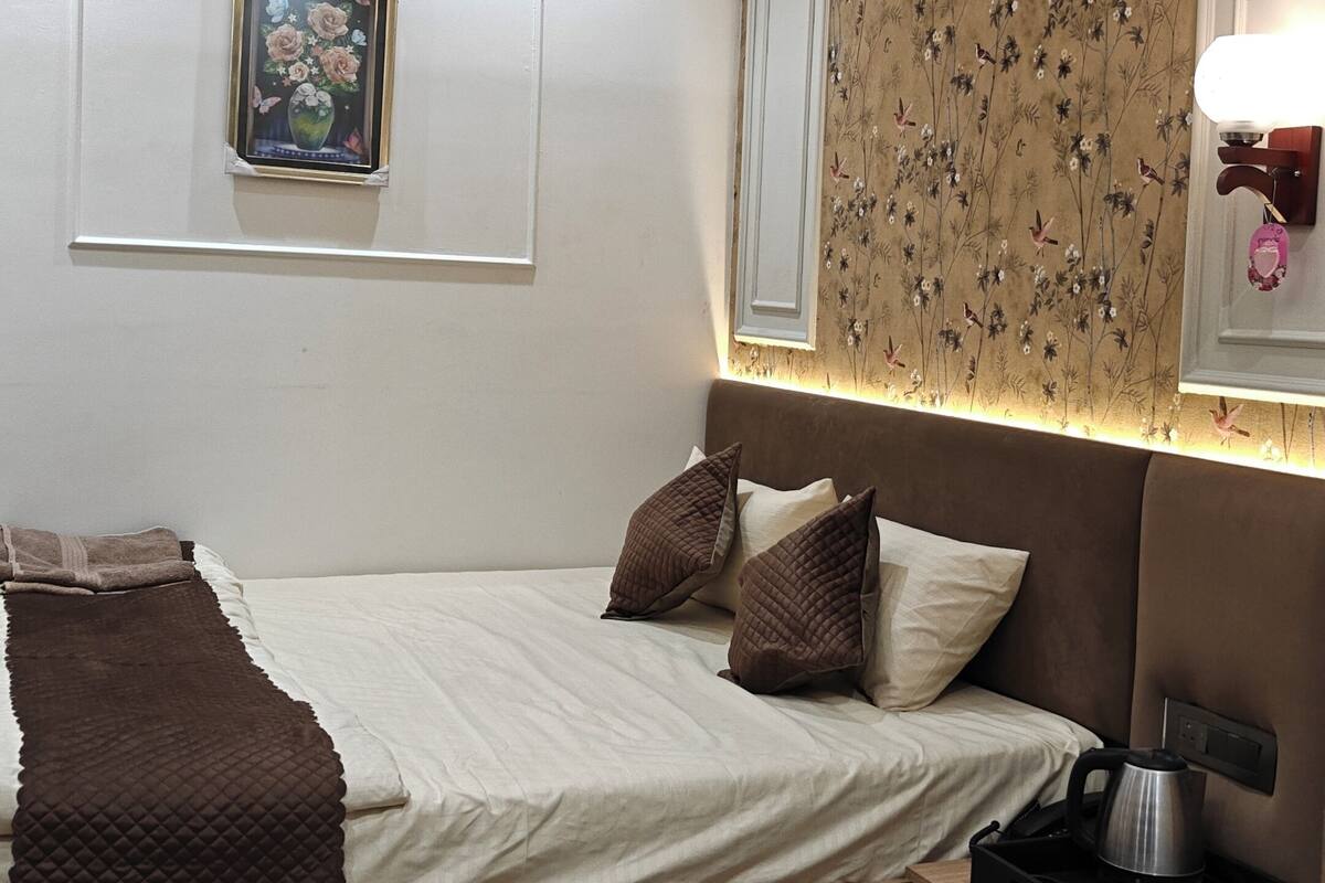 Un dormitorio moderno con una cama, una mesita de noche y una pequeña mesa con una tetera.