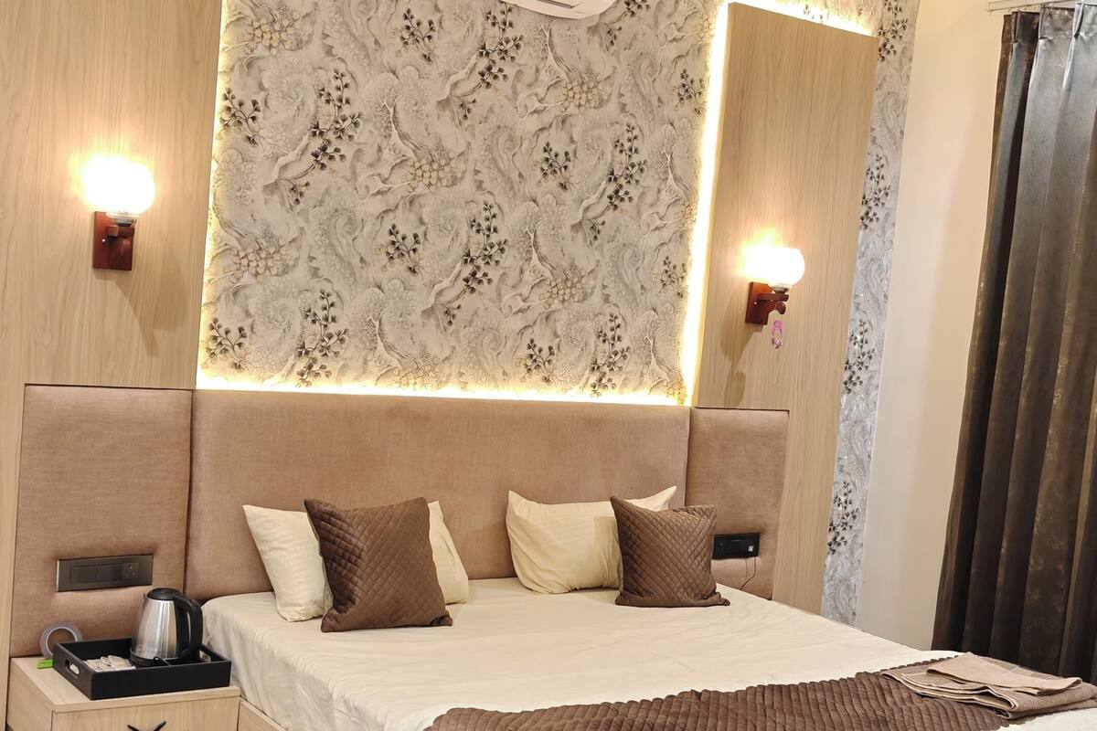 Un dormitorio moderno con cama central, mesitas de noche, equipo de aire acondicionado, ventilador de techo y un panel decorativo en la pared.