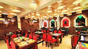 A restaurant with brick walls, red chairs, and hanging wicker lamps. - ATITHI (Hisar)