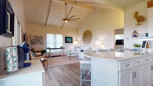 A spacious living area with a high ceiling, a ceiling fan, a dining area, and a kitchen with white cabinetry. - Bolivar Bungalow: 1  BR, 1.5  BA House in Crystal Beach, Sleeps 5 (Crystal Beach)