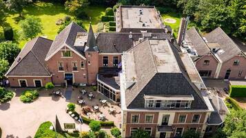 Un grand bâtiment historique doté de plusieurs ailes, d’une cour centrale et d’un jardin bien entretenu.