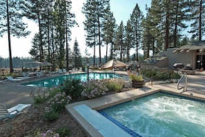 A pool area with lounge chairs, a hot tub, and a barbecue grill.