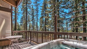 A hot tub on a wooden deck with a table and chairs, surrounded by tall pine trees. - Cascade Hideaway in Lake Village With Private Hot Tub! (Stateline)