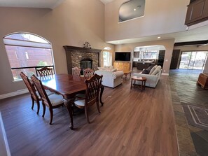 A spacious living area with a dining table, sofas, a fireplace, and a kitchen area.