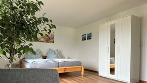 Una camera da letto con un letto, un armadio, un tavolino e una pianta in vaso.