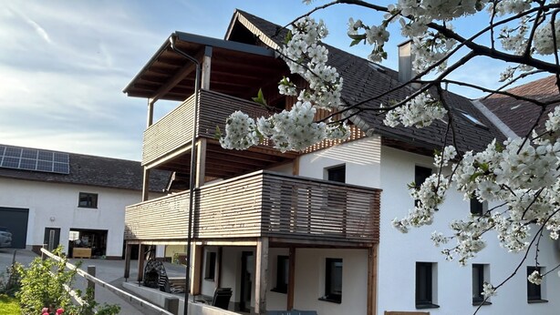 Un edificio a due piani con un balcone, una panchina e un cartello con su scritto 'Lieblingsplatz'.