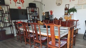 A dining area with a wooden table and chairs, a television, and decorative items on the walls.