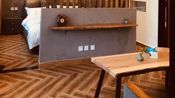 A modern hotel room with a bed, bedside table, and a decorative bamboo screen.