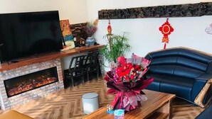 A living room with a fireplace, sofa, coffee table, and decorative plants.