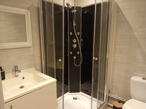 Ein modernes Badezimmer mit einer Duschkabine aus Glas, einem weißen Waschbecken und einer Toilette.