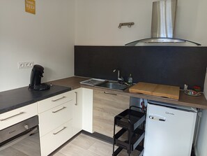 Eine kompakte Küchenzeile mit Kaffeemaschine, Spüle und kleinem Kühlschrank.