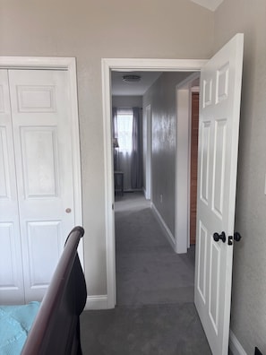 A hallway with white doors, a visible ceiling light, and a carpeted floor.