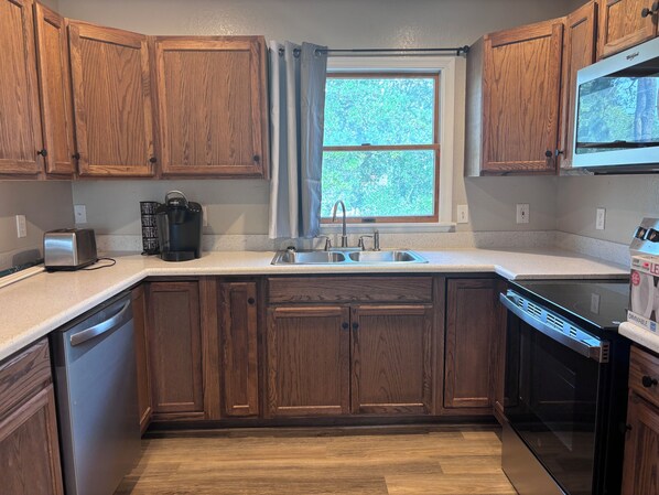 A kitchen with wooden cabinets, a stainless steel sink, a dishwasher, and a coffee maker.