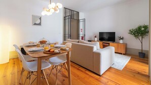 Un salon moderne avec une table à manger, un canapé, un téléviseur et une plante en pot.