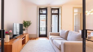 Un salon moderne avec un canapé, un téléviseur, un meuble de rangement en bois et une plante.