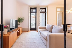 Ein modernes Wohnzimmer mit Sofa, Fernseher, einer Holz-Unterhaltungseinheit und einer Pflanze.
