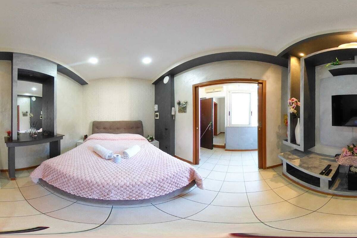 Una habitación de hotel moderna con una cama grande, un escritorio, una silla y un televisor.