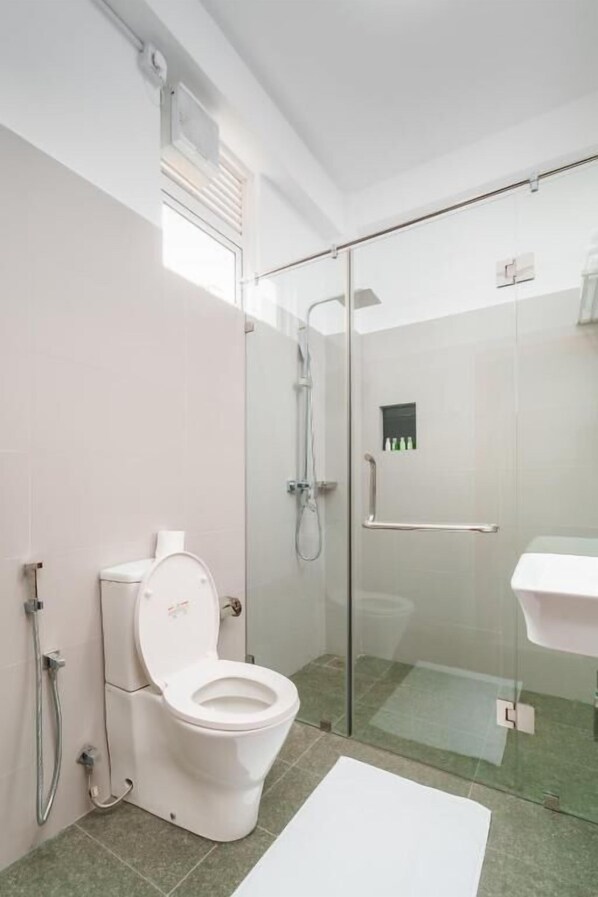 A modern bathroom with a toilet, shower, and glass-enclosed shower area. - SALUDIYA RETREAT RESORT AND SPA (Dambulla)