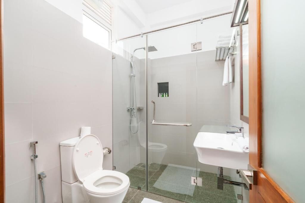 Uma casa de banho moderna com chuveiro de vidro, sanita branca e lavatório.