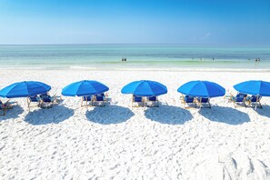 A beach with five blue umbrellas and beach chairs aligned in a row. - New Luxurious 1 BR/2 Ba with 2 Kings and a Queen w/ Free Beach Service for 4! (Fort Walton Beach)