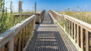A wooden boardwalk leading to a beach, surrounded by tall grasses and clear blue sky. - New Luxurious 1 BR/2 Ba with 2 Kings and a Queen w/ Free Beach Service for 4! (Fort Walton Beach)
