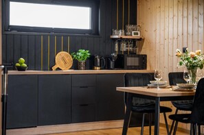 Moderni keittiö, jossa on mustat kaapit, puinen työtaso ja ruokailutila, jossa on pöytä kahdelle.