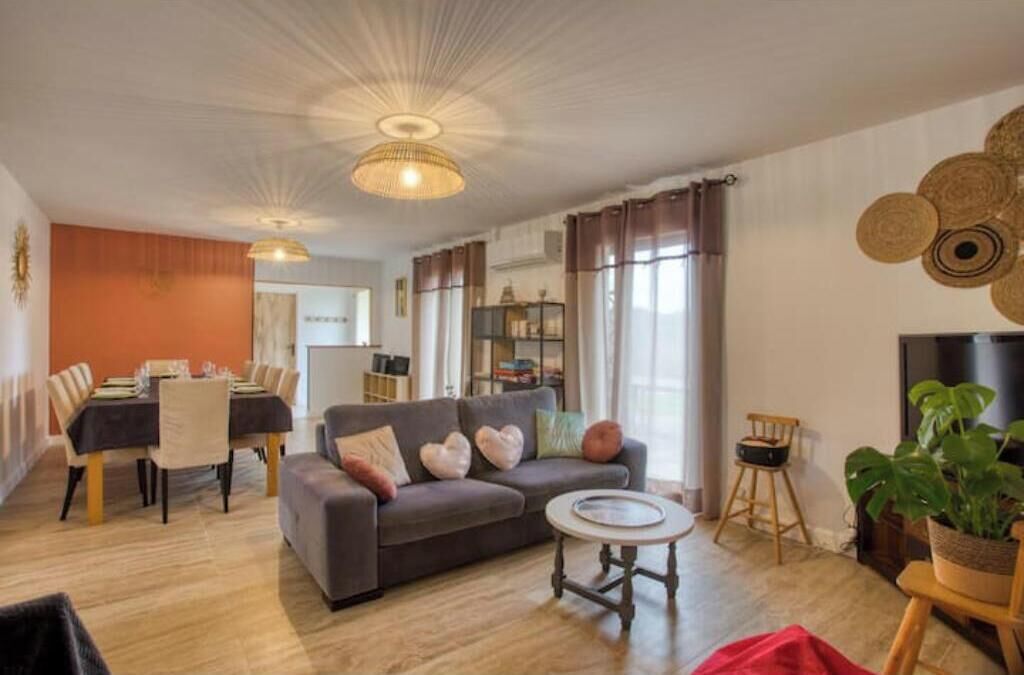 Un salon comprenant un canapé, une table à manger et des chaises, une petite table ronde et un téléviseur.