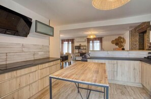 Eine moderne Küche mit einem Holztisch, eingebauten Schränken und einem an der Wand befestigten Fernseher.