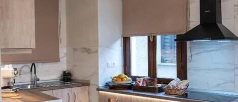 Una cocina con armarios de madera, una mesa de comedor con comida y una ventana con persianas.