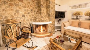 Un camino in pietra, un divano, una televisione e un tavolino in legno in un soggiorno.