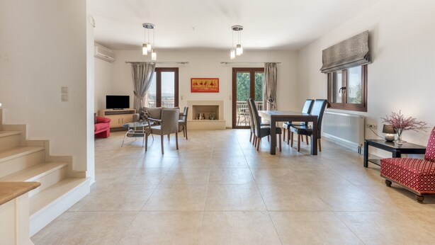 Uma sala de estar ampla com uma mesa de jantar, cadeiras, lareira e televisão.