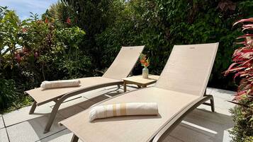 Deux fauteuils confortables avec coussins, une petite table et une plante en pot, le tout dans un cadre de jardin.