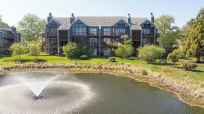 A multi-story building with a pond in the foreground. - Eagle Way 2  Access to Pools (Rehoboth Beach)