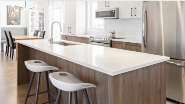 A modern kitchen with a central island, stainless steel appliances, and bar stools. - Beautiful New Home - Min to Airport and Space Museum! (Madison)