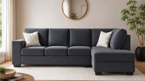 A sectional sofa with a round mirror above it, a potted plant, and a round wooden table with a bowl and book. - Beautiful New Home - Min to Airport and Space Museum! (Madison)