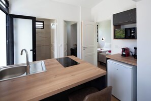 Eine moderne Küche mit Holztischplatte, integriertem Spülbecken, Mikrowelle und kleinem Kühlschrank.