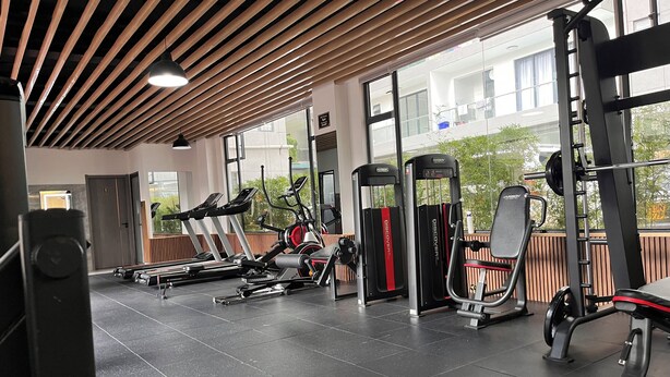 Un gimnasio con equipamiento de ejercicio, ventanas amplias y techo de madera.