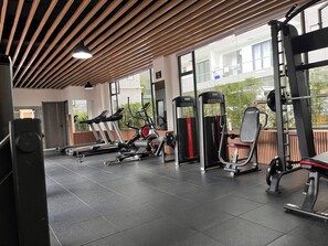 A gym with exercise equipment, large windows, and a wooden ceiling. - Luxury One Bedroom Apartment in Nairobi with Pool & Gym (Nairobi)