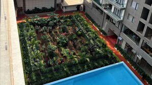 Un edificio alto con jardín en la azotea y piscina.