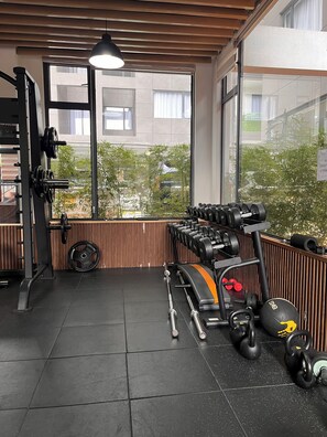 Ein Fitnessraum mit Trainingsgeräten, großen Fenstern und Blick ins Freie.