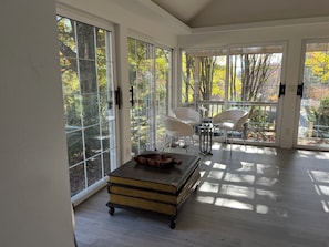 A modern room with large glass doors, a wooden table, and two white chairs.